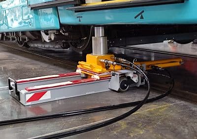 Vérin hydraulique de réenraillement LS FERRO en action sous métro en atelier