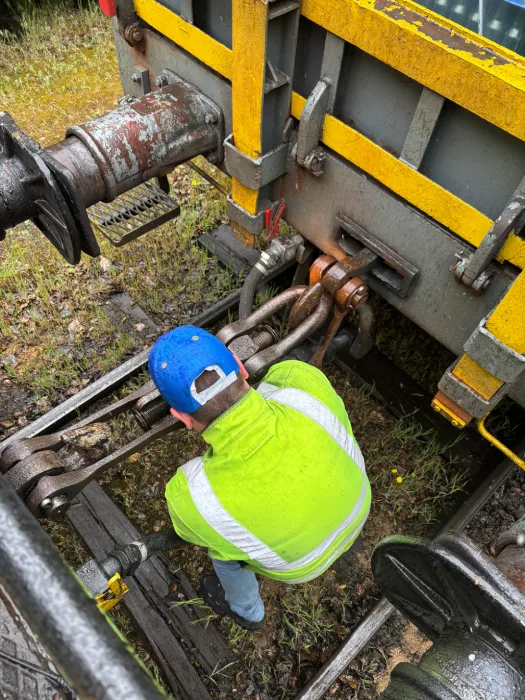 Technicien ferroviaire réalisant un raccordement de wagons sur voie ferrée