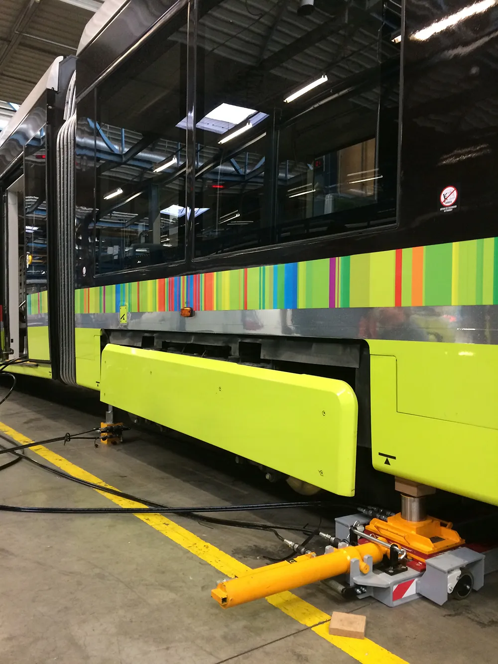 Matériel de levage et de ripage hydraulique positionné sous le châssis d'un tramway en atelier de maintenance